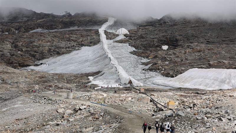 Ein schmales Schneeband: Menschen sind am Mölltaler Gletscher in Kärnten unterwegs.