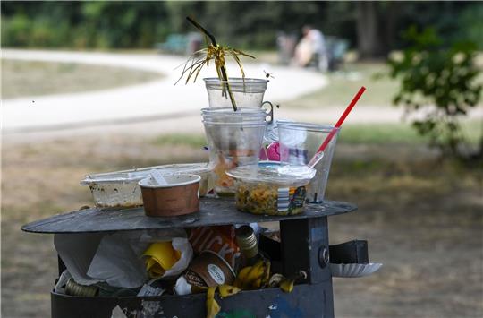 Ein übervoller Mülleimer mit Partymüll im Treptower Park in Berlin. Viele Gaststätten bieten ihrer Kundschaft laut Greenpeace noch immer keine Mehrweg-Verpackungen an.