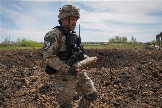 Ein ukrainischer Soldat sammelt nicht explodierte Granaten ein.