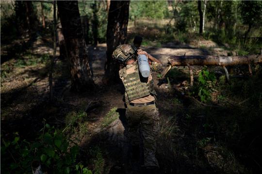 Ein ukrainischer Soldat trägt eine Granate an der Frontlinie in Lyman.