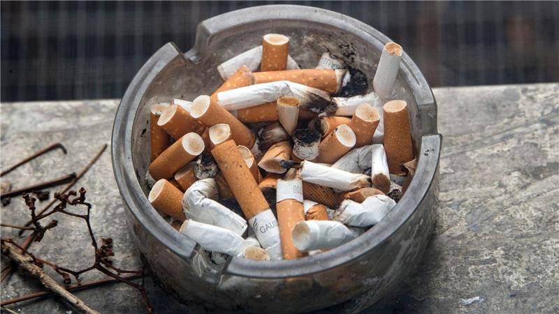 Ein voller Aschenbecher steht auf einem Fensterbrett.