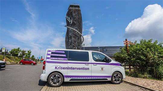 Weißer Transporter mit der Aufschrift „Krisenintervention“ steht vor dem Harzturm