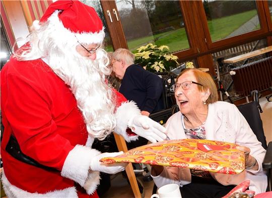 Eine 98-jährige Seniorin nimmt freudestrahlend ein Geschenk vom Weihnachtsmann entgegen. Zuvor hat sie sich wie viele andere Heimbewohnerin darüber gewundert, was der Weihnachtsmann alles über sie weiß .... Foto: Kusian-Müller