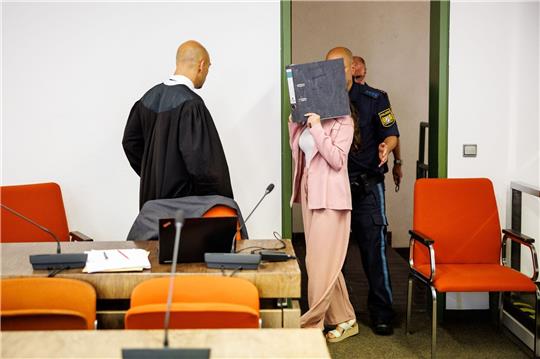 Eine Angeklagte (M), die sich der Terrormiliz Islamischer Staat beim Betreten des Gerichtssaals.