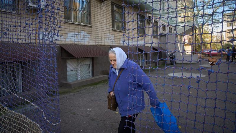 Eine Anwohnerin geht durch einem mit einem Anti-FPV-Drohnennetz bedeckten Hof in der Frontstadt Cherson in der Südukraine.