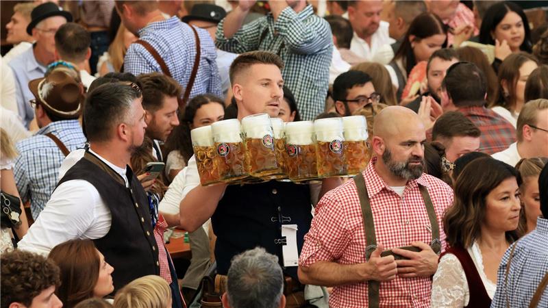Eine Bedienung schleppt Maßkrüge durch ein Wiesn-Festzelt.