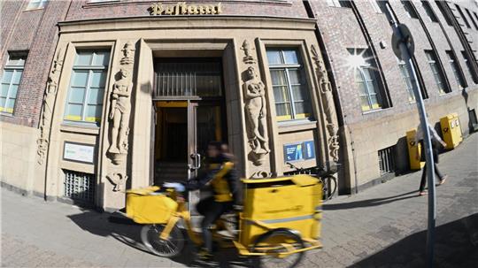Eine Briefträgerin fährt an einer Postfiliale vorbei - vielleicht ist auch sie eine Beamtin?