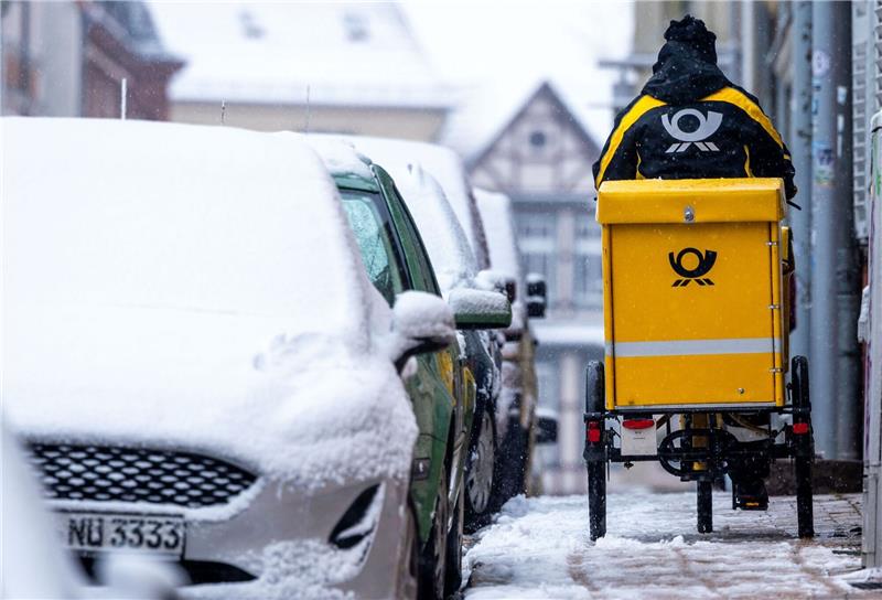 Tarifeinigung bei der Deutschen Post: Streik wohl abgewendet Eine Briefträgerin ist mit ihrem Fahrrad in der Altstadt von Schwerin unterwegs.