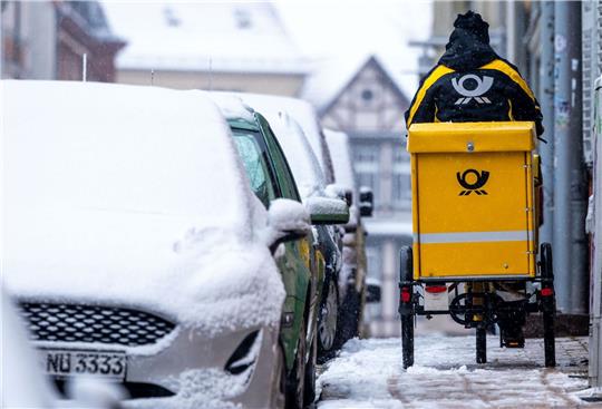 Eine Briefträgerin ist mit ihrem Fahrrad in der Altstadt von Schwerin unterwegs.