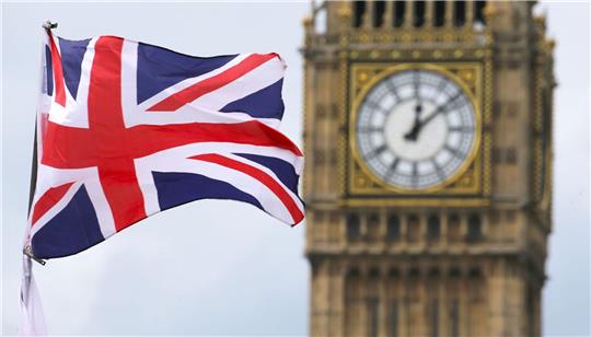 Eine Britische Fahne weht vor dem berühmten Uhrturm Big Ben in London.