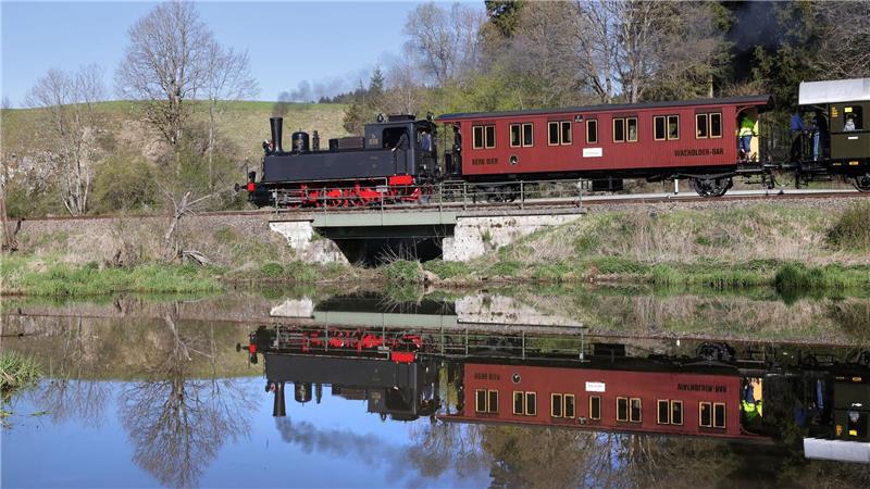 Eine Dampflokomotive ist auf der Schwäbischen Alb unterwegs und spiegelt sich in einem Gewässer.