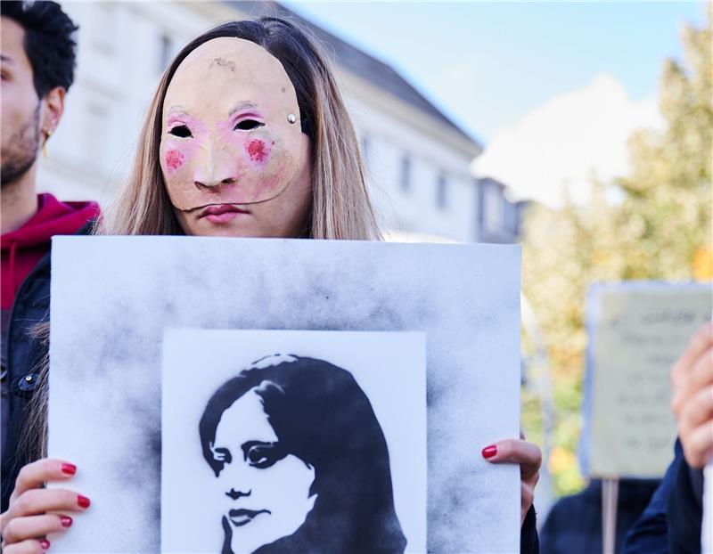 100 Tage nach Jina Mahsa Aminis Tod: Teheran in der Krise Eine Demonstrantin hält in Berlin eine Abbildung der getöteten Kurdin Jina Mahsa Amini in die Höhe.
