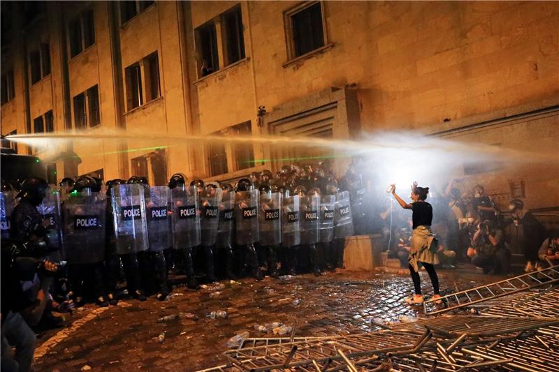 Mehr als 60 Festnahmen bei Protesten in Tiflis Eine Demonstrantin steht in Tiflis Bereitschaftspolizisten gegenüber.