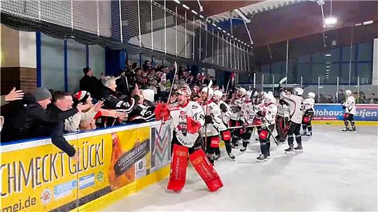 Eine Einheit: Die Harzer Falken um Torwart Taylor Dupuis und die mitgereisten Fans feiern kurz vor Mitternacht gemeinsam den dramatischen 3:2-Sieg in Harsefeld.