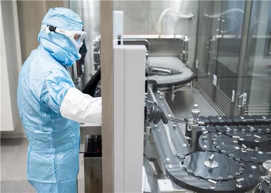 Eine Fachkraft steht an einer Abfüll- und Verschließanlage für pharmazeutische Produkte eines Unternehmens in Singen (Hohentwiel).