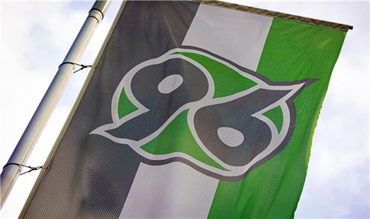 Eine Fahne mit dem Logo von Hannover 96 weht vor der Heinz von Heiden-Arena.