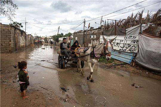 Eine Familie fährt mit einer Kutsche über einen überschwemmten Weg. Schwere Regenfälle und Überschwemmungen beeinträchtigen das tägliche Leben der Palästinenser in der Stadt Khan Yunis im südlichen Gazastreifen.
