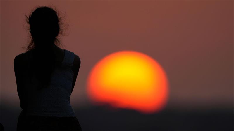 Eine Frau beobachtet den Sonnenuntergang.