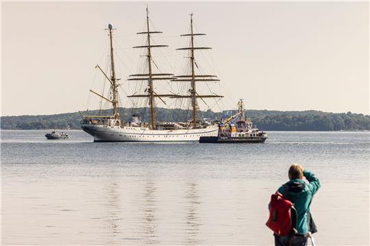 Eine Frau beobachtet vom Ufer aus die «Gorch Fock» in der Innenförde.