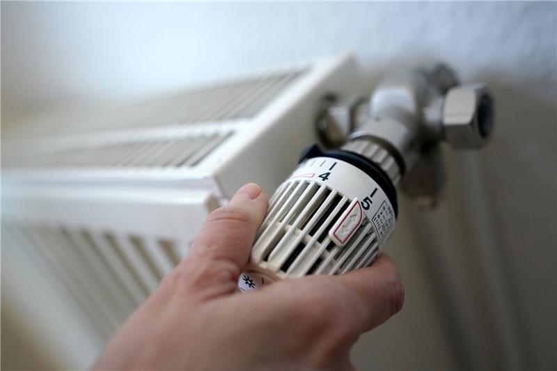 Geteiltes Echo auf das Heizungsgesetz Eine Frau dreht an einem Heizungsthermostat.