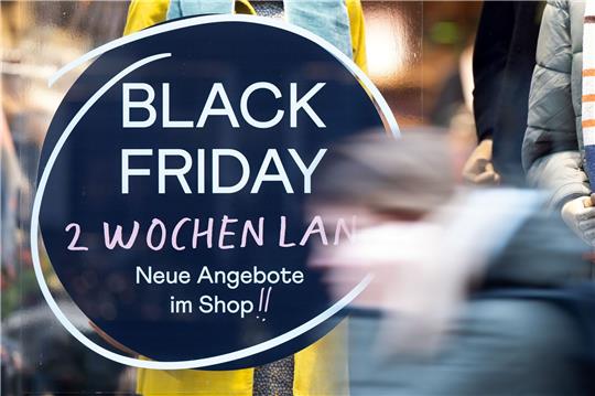 Eine Frau geht an einem Geschäft vorbei, das mit Black Friday-Angeboten wirbt.