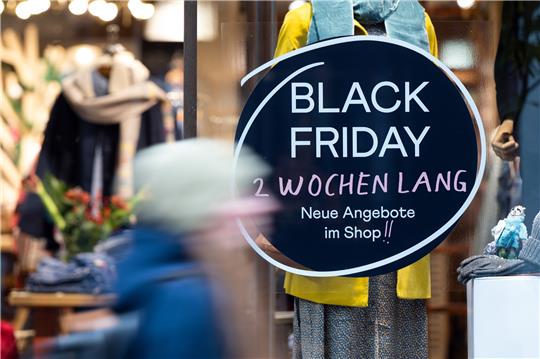Eine Frau geht an einem Geschäft vorbei, das mit Black Friday-Angeboten wirbt. Der Einzelhandel in Deutschland rechnet an den bevorstehenden Rabatt-Aktionstagen Black Friday und Cyber Monday mit Rekordumsätzen. Foto: Federico Gambarini/dpa