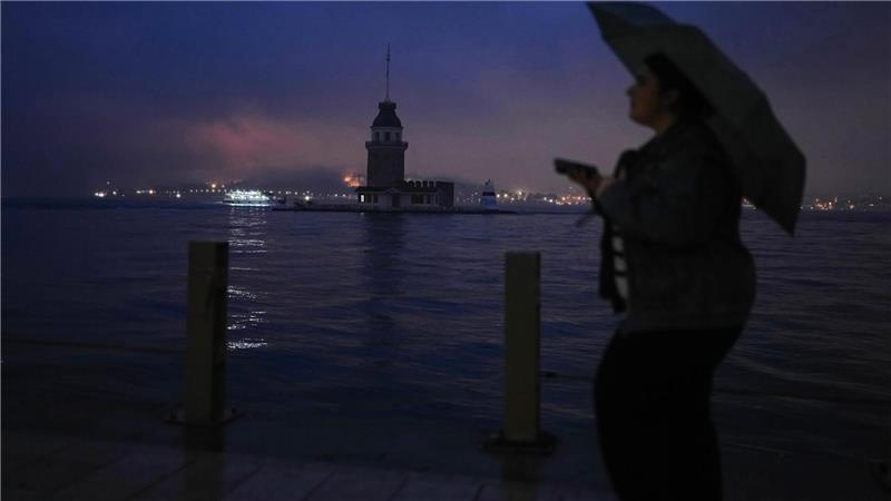 Eine Frau geht an einem regnerischen Tag in Istanbul am Jungfernturm am Bosporus vorbei.