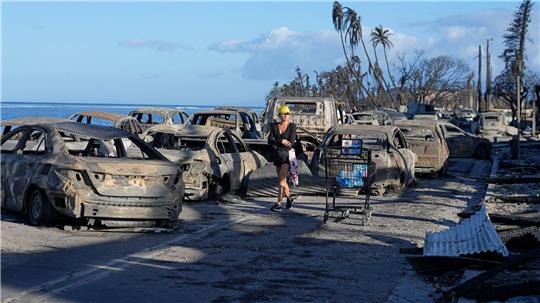 Eine Frau geht an zurückgebliebenen Trümmern nach dem Waldbrand in Lahaina vorbei.