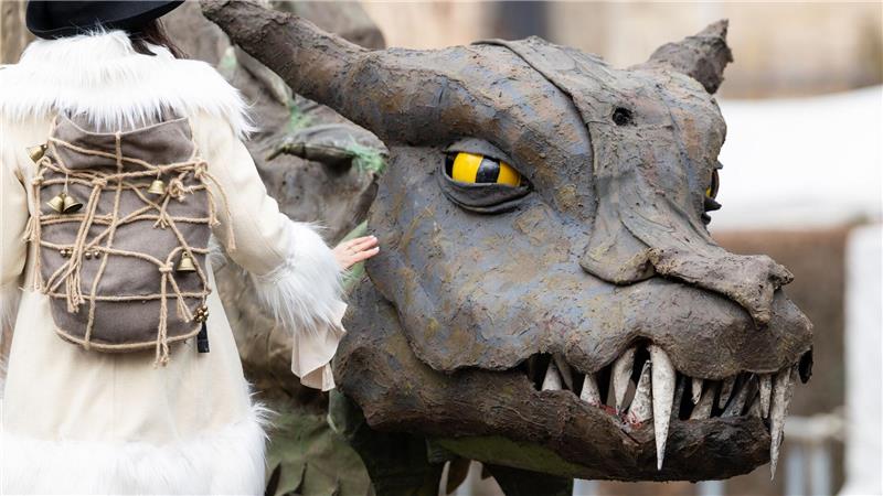Eine Frau geht beim Mittelalterfest auf der Niederburg in Kranichfeld am Drachen Fangdorn vorbei. Am Karsamstag finden im Freistaat zahlreiche Veranstaltungen und Gottesdienste statt.