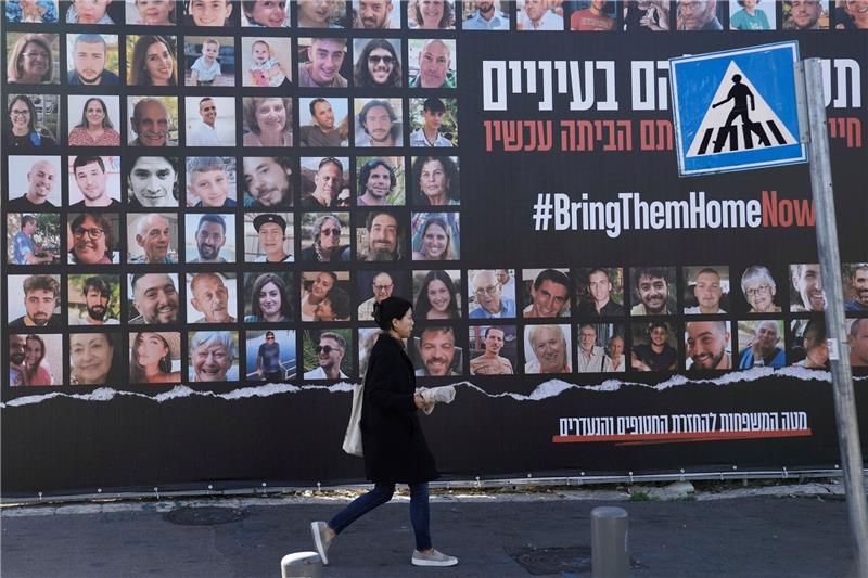 Gaza-Krieg: Was bedeuten Kampfpause und Geisel-Freilassung? Eine Frau geht in Jerusalem an einem Plakat vorbei, das die Rückkehr der etwa 240 Geiseln fordert.