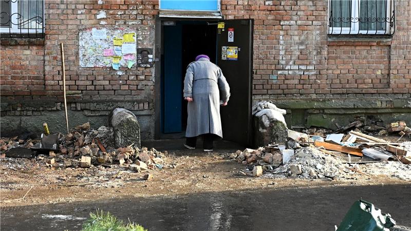 Eine Frau geht in ein beschädigtes Haus.