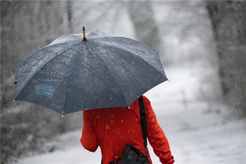 Wetter in Deutschland bleibt grau und ungemütlich Eine Frau geht mit Regenschirm durch den Schnee. Stellenweise kann es in den kommenden Tagen in Deutschland wieder schneien.