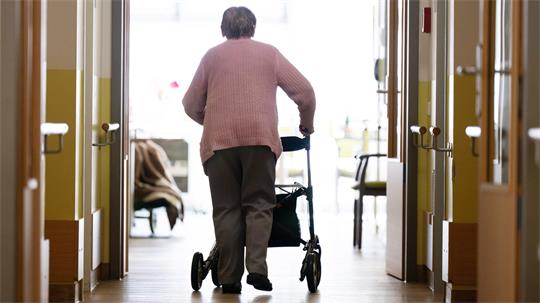 Eine Frau geht an einem Rollator.