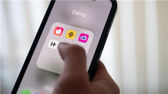 Eine Frau hält ein Smartphone, auf dem Dating-Apps angezeigt werden. (Symbolbild)