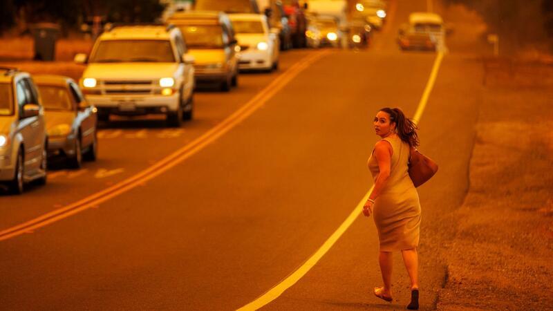 Waldbrände in Kalifornien: Tausende evakuiert Eine Frau läuft an einer Straße während das Thompson-Feuer brennt