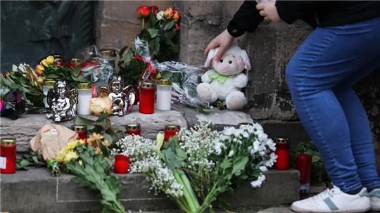 Eine Frau legt am Gedenkort an der Johanniskirche in Magdeburg ein Plüschtier nieder.