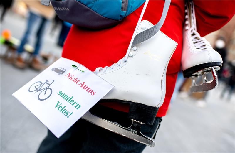 Eine Frau nimmt mit Schlittschuhen und einem Zettel mit der Aufschrift «Nicht Autos sondern Velos!» an einer Demonstration. Foto: picture alliance/dpa | Hauke-Christian Dittrich