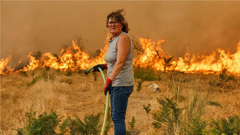 Bilder des Tages Eine Frau schaut erschöpft, als sie versucht, mit einem Schlauch gegen die Ausbreitung eines Feuers in Santa Baia De Montes in Spanien anzukämpfen.