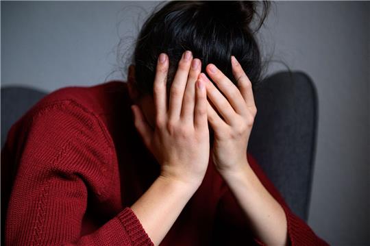 Eine Frau sitzt mit dem Kopf in den Händen auf einem Stuhl. Eltern fühlen sich mehr und mehr gestresst.