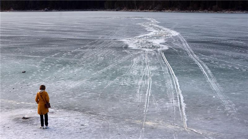 Eine Frau steht am Ufer des zugefrorenen Eibsees, nahe der Stelle an der am Nachmittag mehrere Menschen im Eis eingebrochen waren.