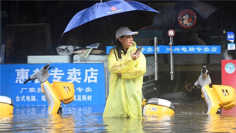 Eine Frau steht in Qinzhou auf einer mit Wasser vollgelaufenen Straße.