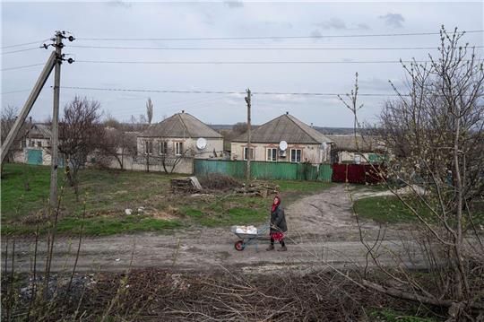 Eine Frau transportiert in Lyman im umkämpften Osten der Ukraine Hilfsgüter auf einer Schubkarre.