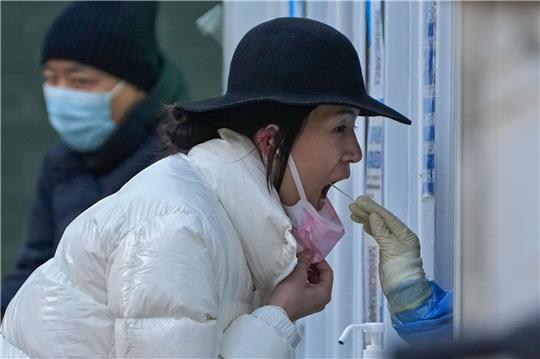 Eine Frau unterzieht sich in einer Coronavirus-Teststelle in Peking einem routinemäßigen COVID-19-Rachenabstrich.