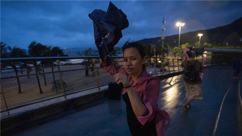Eine Frau versucht, nach dem Super-Taifun Ragasa in Shenzhen in der südchinesischen Provinz Guangdong einen Regenschirm im Wind zu öffnen.