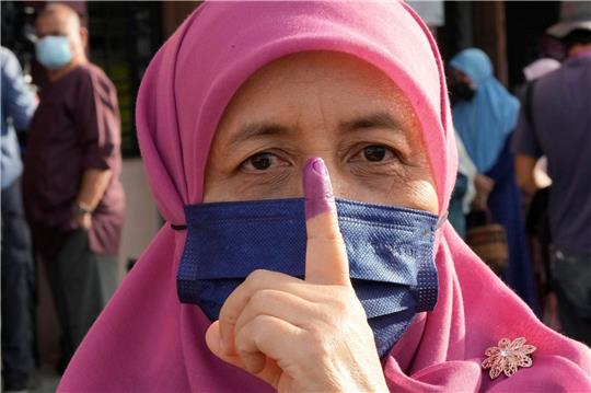 Eine Frau zeigt ihren eingefärbten Finger nach der Stimmabgabe in Seberang Perai.