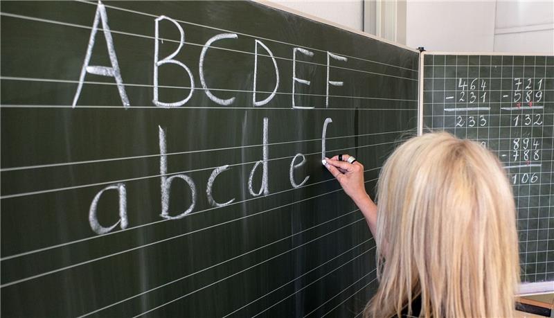 Mehr Plätze für Schulkinder mit Förderbedarf in Bremen Eine Grundschullehrerin schreibt die ersten Buchstaben des Alphabets auf eine Schultafel in einem Klassenzimmer.
