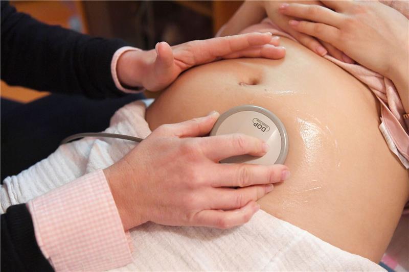 Eine Hebamme hört die Herztöne eines Babys ab.