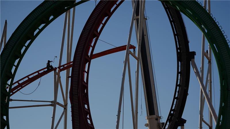 Eine Höhenkletterin nimmt in luftiger Höhe während der Aufbauarbeiten des Frühlingsdoms eine Schiene der Achterbahn auf dem Heiligengeistfeld in Hamburg entgegen.