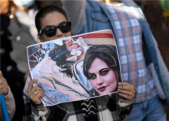 Eine Iranerin beteiligt sich in Frankfurt an einer Demonstration gegen das politische Regime im Iran. Dabei hält sie ein Plakat mit dem Bild der 22-jährigen  Mahsa Amini in den Händen.