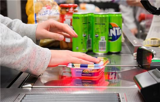 Eine Kassiererin scannt Lebensmittel an der Kasse eines Supermarktes.
